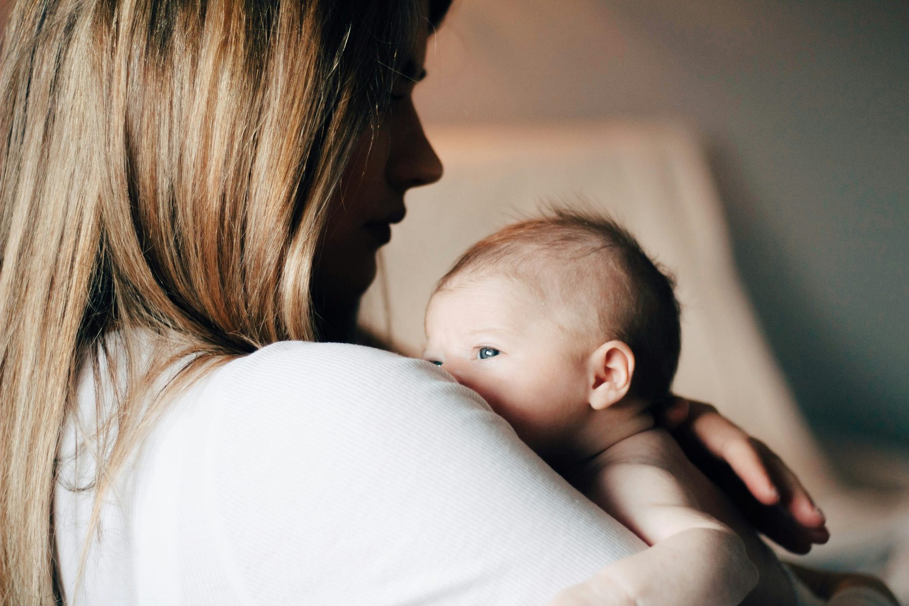A parent holding their baby in warm natural light